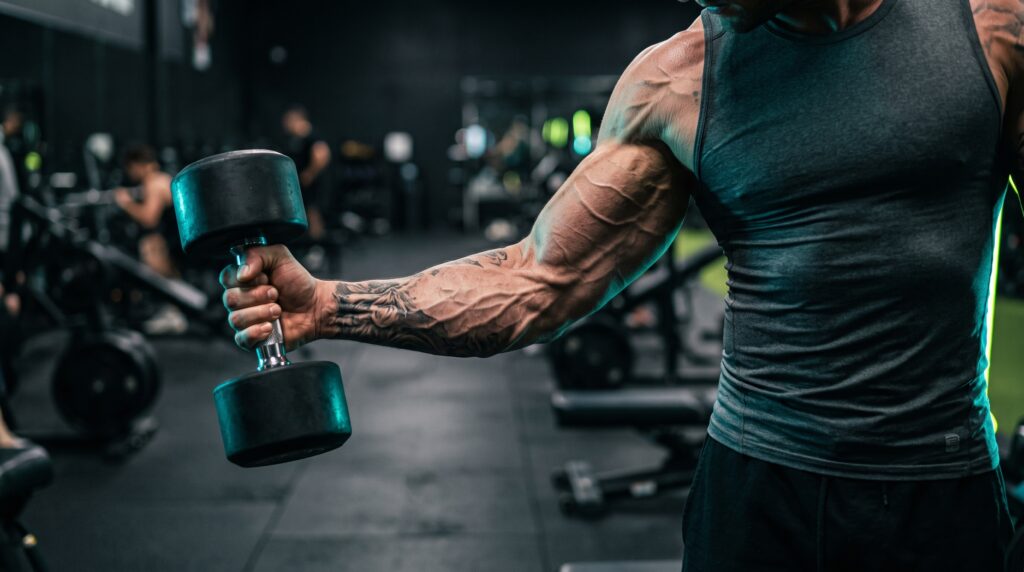 A lifter's fully stretched biceps at the bottom of a dumbbell curl under teal and electric-lime rim light